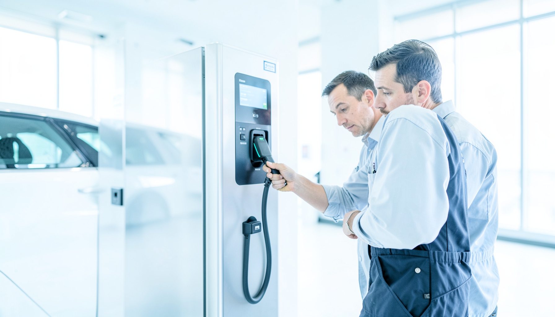 Bright, airy photograph of a technician inspecting an electric vehicle charging station in a modern facility, clean white and silver tones